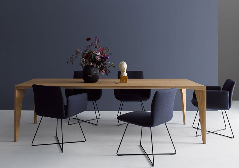 Eine Sitzgruppe der Marke Cor mit fünf dunkelblauen Stühlen und einem Esstisch aus hellem Holz.